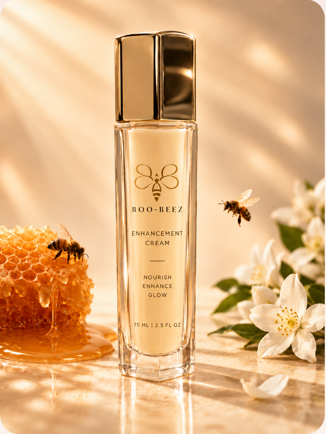 Boo-Beez Daily Ritual Cream in a tall glass bottle with a gold cap, beside honeycomb, honeybees and white blossoms